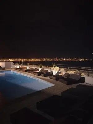 a swimming pool at night with a view of the ocean at A310 Lagoon Beach Apartment & Spa in Cape Town