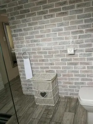 a bathroom with a toilet and a brick wall at Posto Al Sole - IL Bacio in Bellville