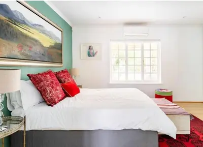 a bedroom with a large white bed with red pillows at Art House in Stellenbosch