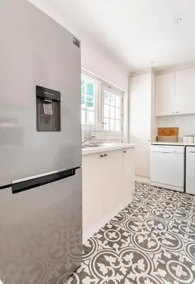 a kitchen with white cabinets and a tile floor at Art House in Stellenbosch