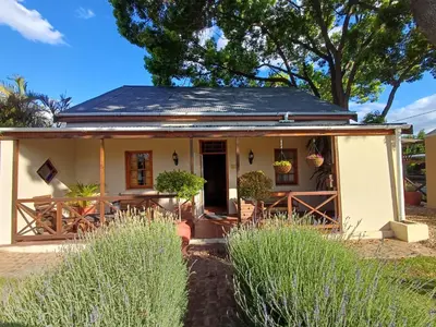 a small white house with a porch at Die Heemhuis in Rawsonville