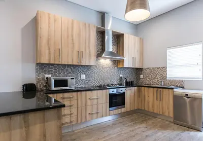 a kitchen with wooden cabinets and a microwave at Suburban Bliss Durbanville in Kraaifontein