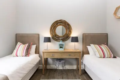 a bedroom with two beds and a mirror on the wall at Suburban Bliss Durbanville in Kraaifontein