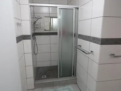 a shower with a glass door in a bathroom at Easy Five Guest House in Somerset West