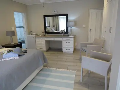 a bedroom with a bed and a dresser with a mirror at Easy Five Guest House in Somerset West