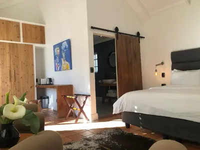 a bedroom with a bed and a door leading to a bathroom at Tempel Wines in Paarl