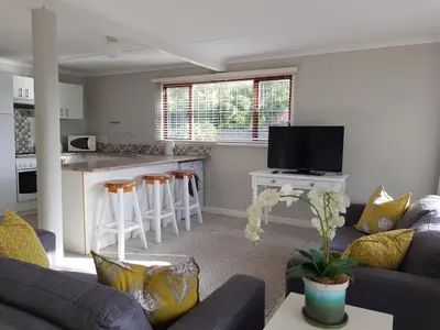 a living room with a couch and a kitchen at Drommedaris in Gordonʼs Bay