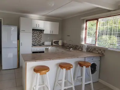 a kitchen with a counter and two stools at Drommedaris in Gordonʼs Bay