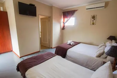 a hotel room with two beds and a flat screen tv at Ramasibi Guest Services in Panorama