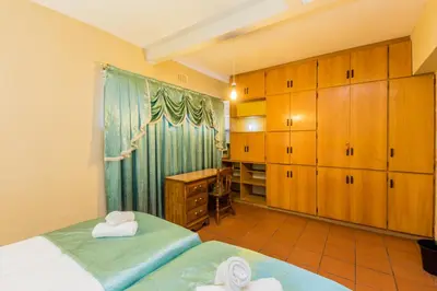 a bedroom with two beds and a desk and cabinets at AJEE B&B in Paarl