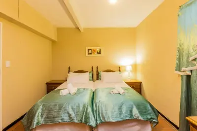 a bedroom with a bed with green sheets at AJEE B&B in Paarl