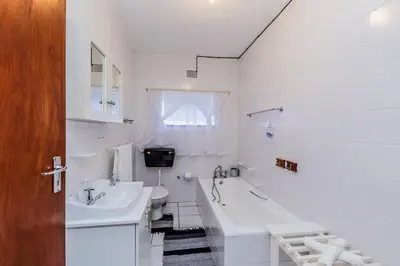 a white bathroom with a tub and a sink and a bath tub at AJEE B&B in Paarl
