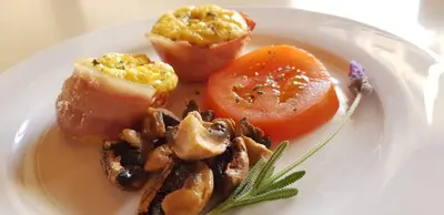 a white plate of food with mushrooms and tomatoes at AJEE B&B in Paarl