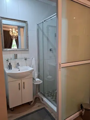 a bathroom with a glass shower and a sink at Leeuwenhof Guesthouse in Caledon
