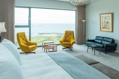 a hotel room with a bed and chairs and a large window at Schulphoek Seafront Boutique Hotel in Hermanus