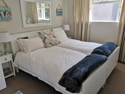 a white bed with a blue blanket on it in a bedroom at On Cloud 9 in Hermanus