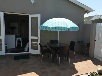a table and chairs with an umbrella on a patio at On Cloud 9 in Hermanus