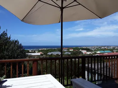 an umbrella on a balcony with a view of the ocean at The Trailhouse - Betty's Bay in Bettyʼs Bay