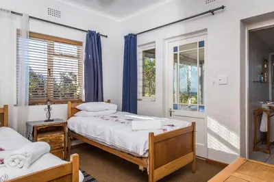 a bedroom with two beds and a shower at The Trailhouse - Betty's Bay in Bettyʼs Bay