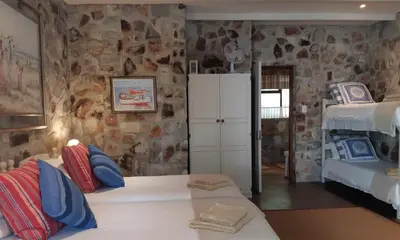 a bedroom with two beds and a stone wall at Braeview Guest House in Hermanus
