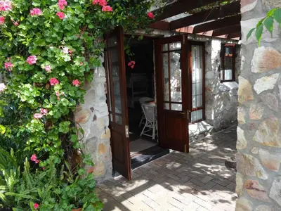 an entrance to a stone building with pink flowers at Braeview Guest House in Hermanus