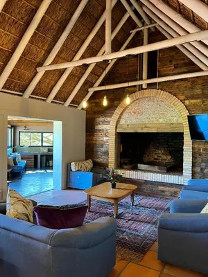 a living room with a fireplace and blue couches at Rivers Own Guest Lodge in Breerivier