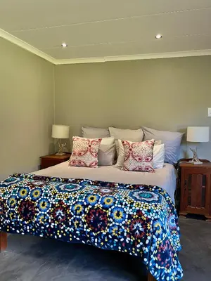 a bedroom with a large bed with colorful pillows at Rivers Own Guest Lodge in Breerivier