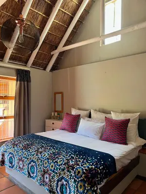 a bedroom with a large bed with colorful pillows at Rivers Own Guest Lodge in Breerivier