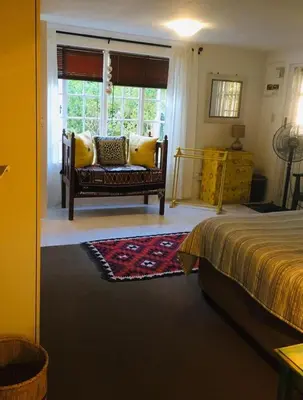 a bedroom with a bed and a couch and a window at Funky cottage in Hermanus