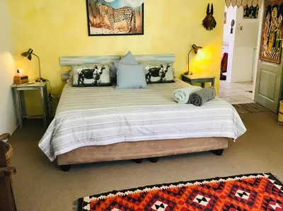 a bedroom with a large bed with pillows at Funky cottage in Hermanus