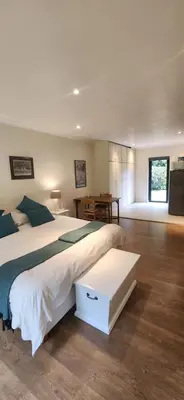 a bedroom with a large white bed and a desk at Guinea Vine in Stellenbosch