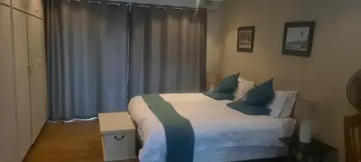 a bedroom with a bed with blue and green pillows at Guinea Vine in Stellenbosch