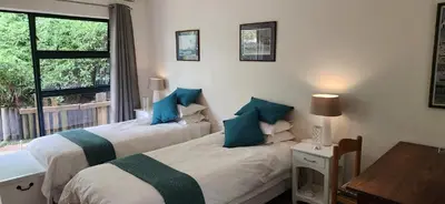 two beds in a room with a window at Guinea Vine in Stellenbosch