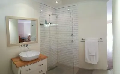 a white bathroom with a sink and a mirror at Guinea Vine in Stellenbosch