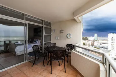 a balcony with a table and chairs and a bedroom at Blakes Terrace 903 in Strand