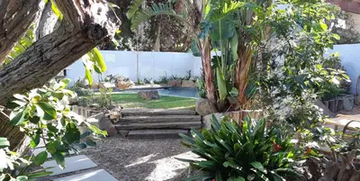a garden with a pool and some trees and plants at Be My Guest Lodge in Bloubergstrand