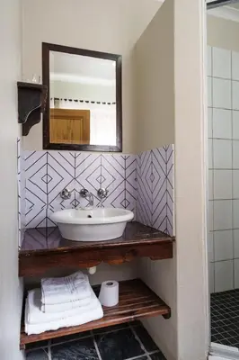 a bathroom with a sink and a mirror at Be My Guest Lodge in Bloubergstrand