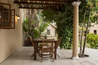 a table and chairs under a pergola on a patio at The Country Guesthouse in Stellenbosch