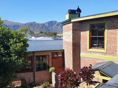 a brick house with mountains in the background at Port Del Mar Guesthouse in Hermanus