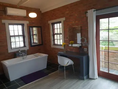 a bathroom with a tub and a sink and a mirror at Port Del Mar Guesthouse in Hermanus