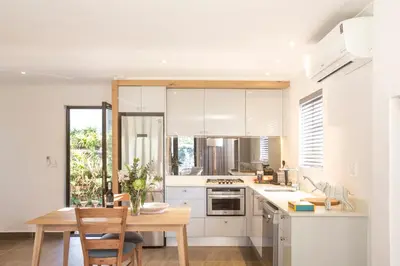 a kitchen with white cabinets and a wooden table at Mont Angelis in Stellenbosch