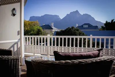 a balcony with a chair and a table and a fence at Westbury House Guest House in Cape Town