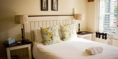 a bedroom with a white bed with pillows and two lamps at Westbury House Guest House in Cape Town