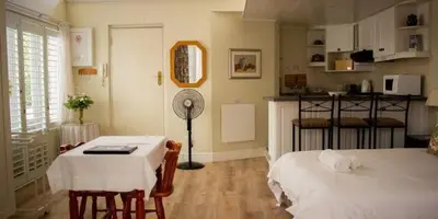 a room with a table and a bed and a kitchen at Westbury House Guest House in Cape Town