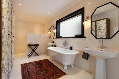 a bathroom with a tub and a sink and a mirror at MolenVliet Estate - Boutique Bed & Breakfast in Stellenbosch
