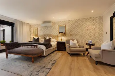 a large bedroom with a bed and two chairs at MolenVliet Estate - Boutique Bed & Breakfast in Stellenbosch
