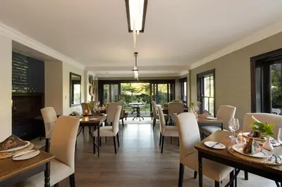 a dining room with tables and chairs and windows at MolenVliet Estate - Boutique Bed & Breakfast in Stellenbosch