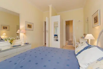 a large bedroom with a blue bed and a bathroom at Jewel of Bayview in Hermanus