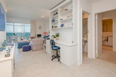 a kitchen and living room with a desk and a living room at Jewel of Bayview in Hermanus