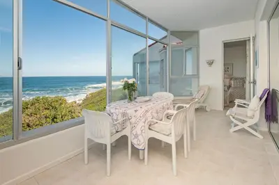 a dining room with a table and chairs and the ocean at Jewel of Bayview in Hermanus